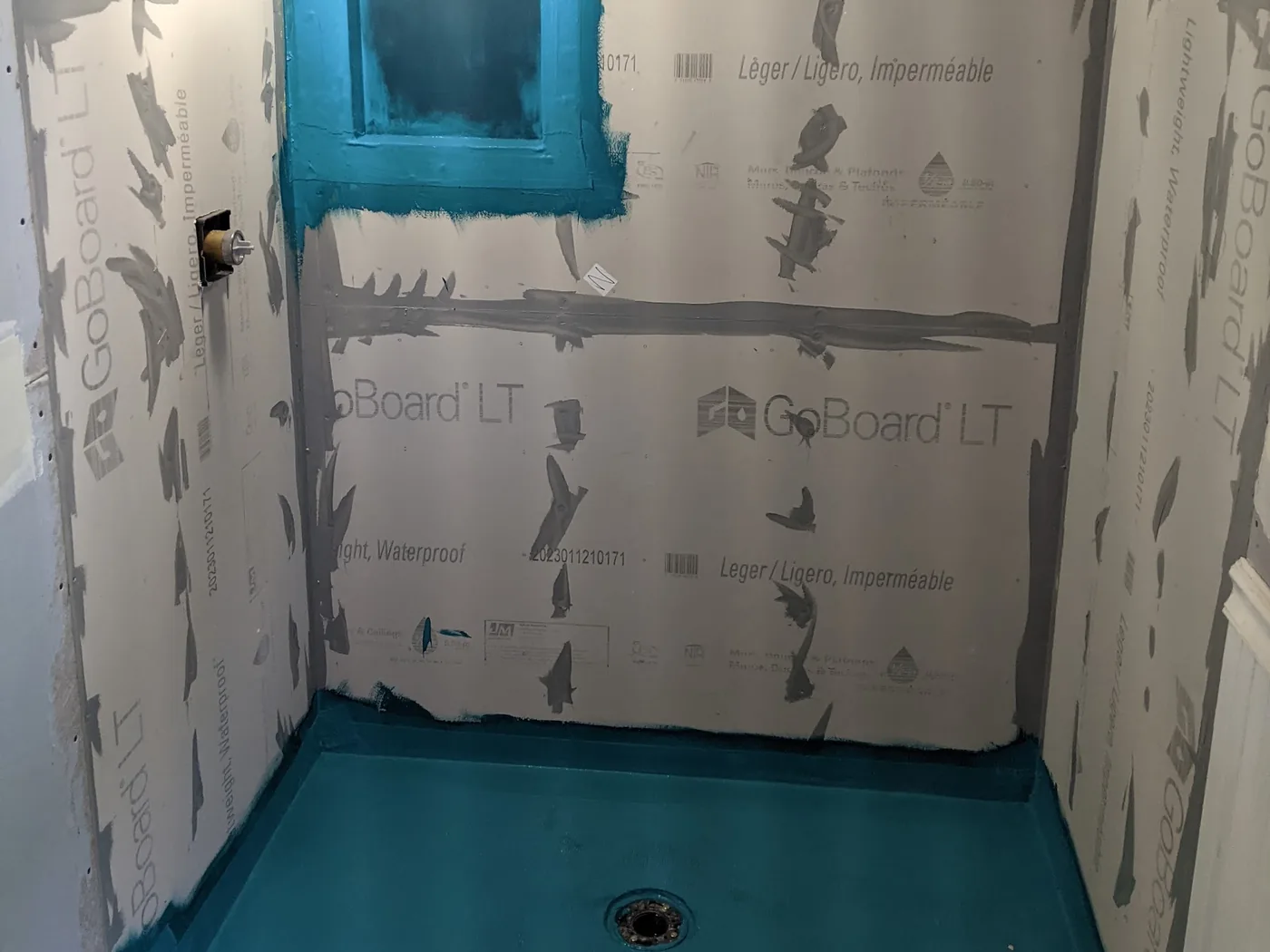 Shower walls and pan covered in a bonded waterproofing membrane with taped seams and a sloped pan, before any tile, in a Hazlet, NJ bathroom remodel