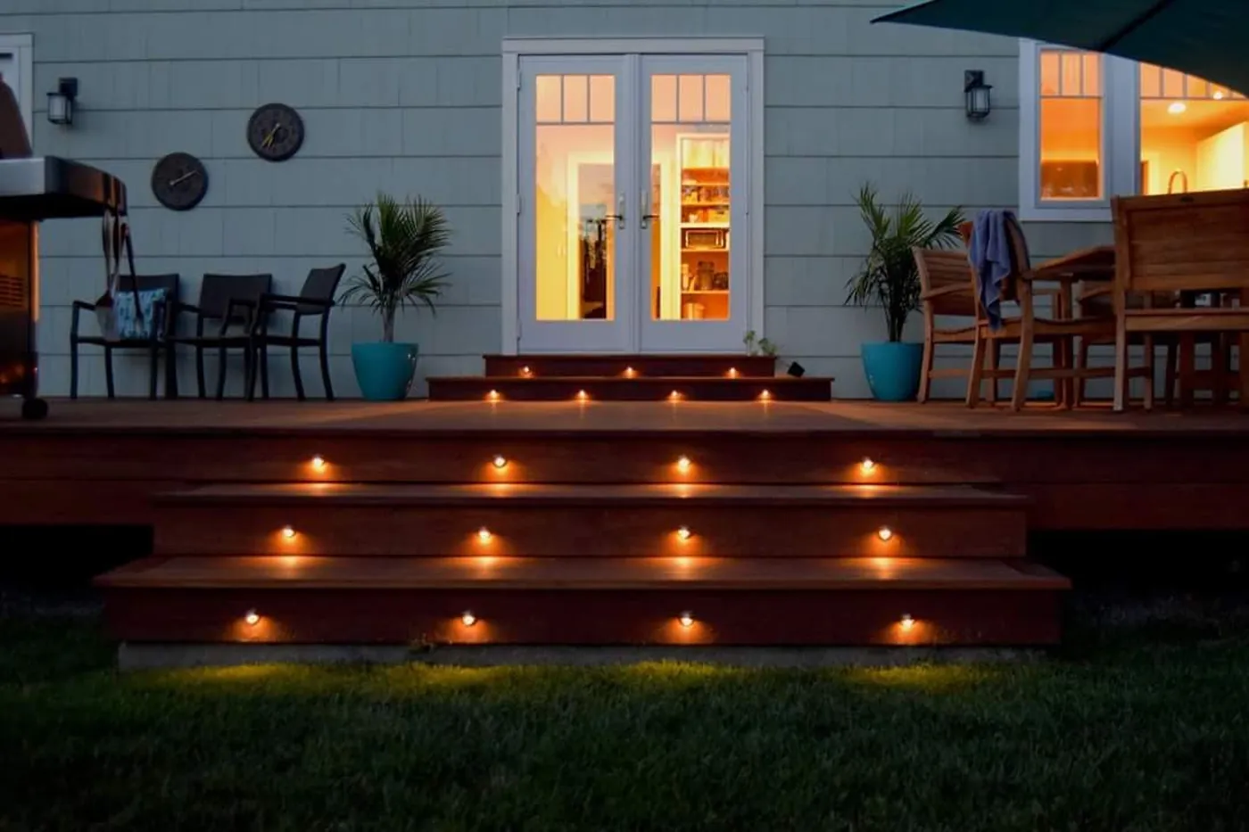 Ipe hardwood deck with lit steps and a black railing at dusk behind a Monmouth County, NJ home, built by RSC Contracting