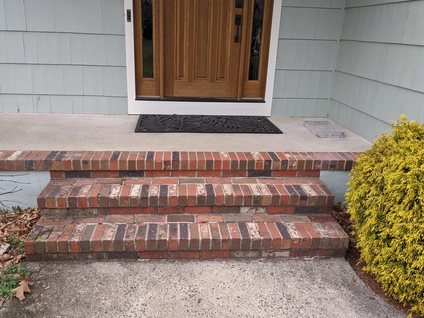Before: an oak entry door with sidelights above brick steps and a concrete stoop on a shingle-sided Monmouth County, NJ home
