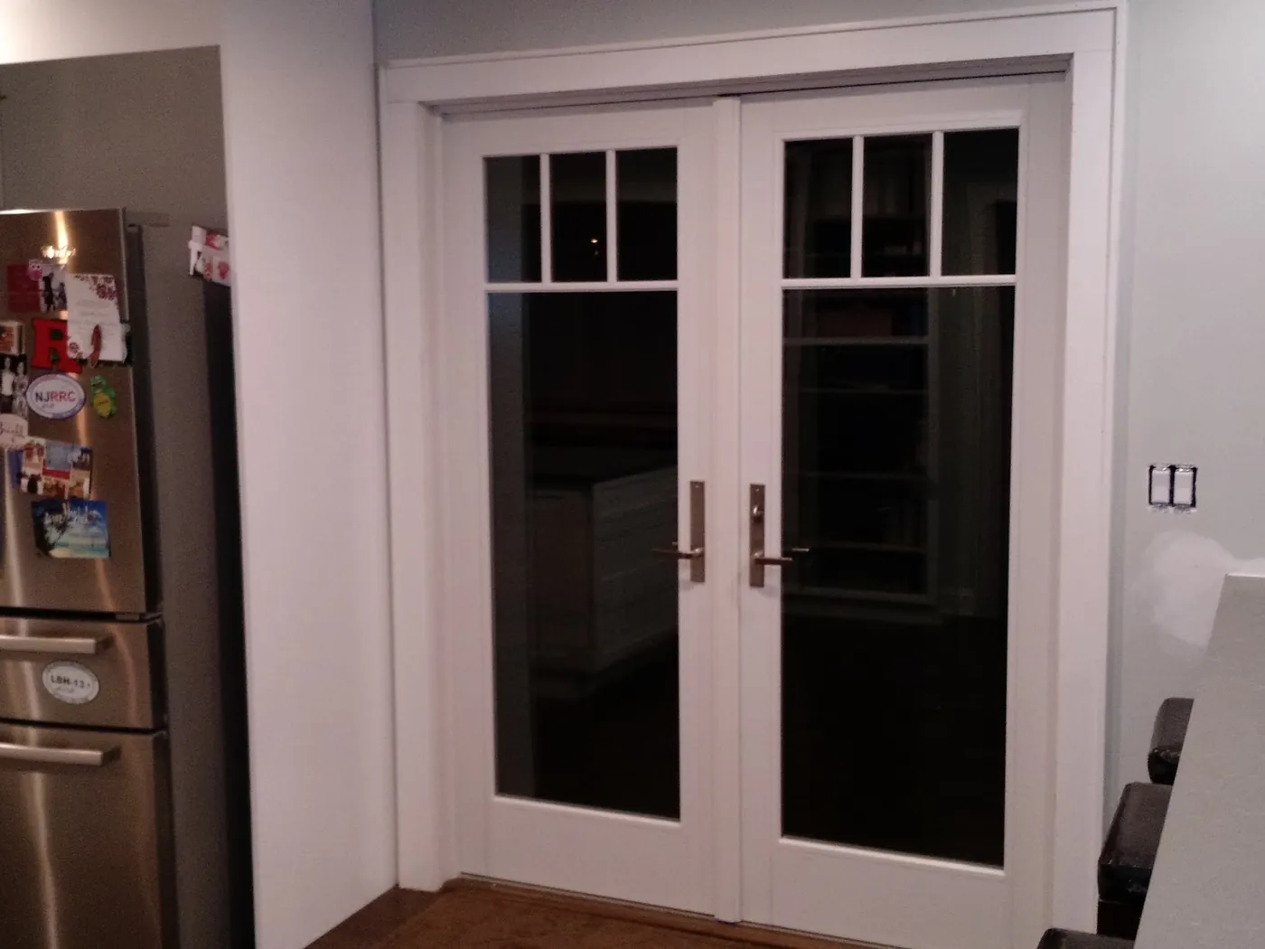 White hinged French doors with divided-lite transoms opening off a kitchen in a Monmouth County, NJ home