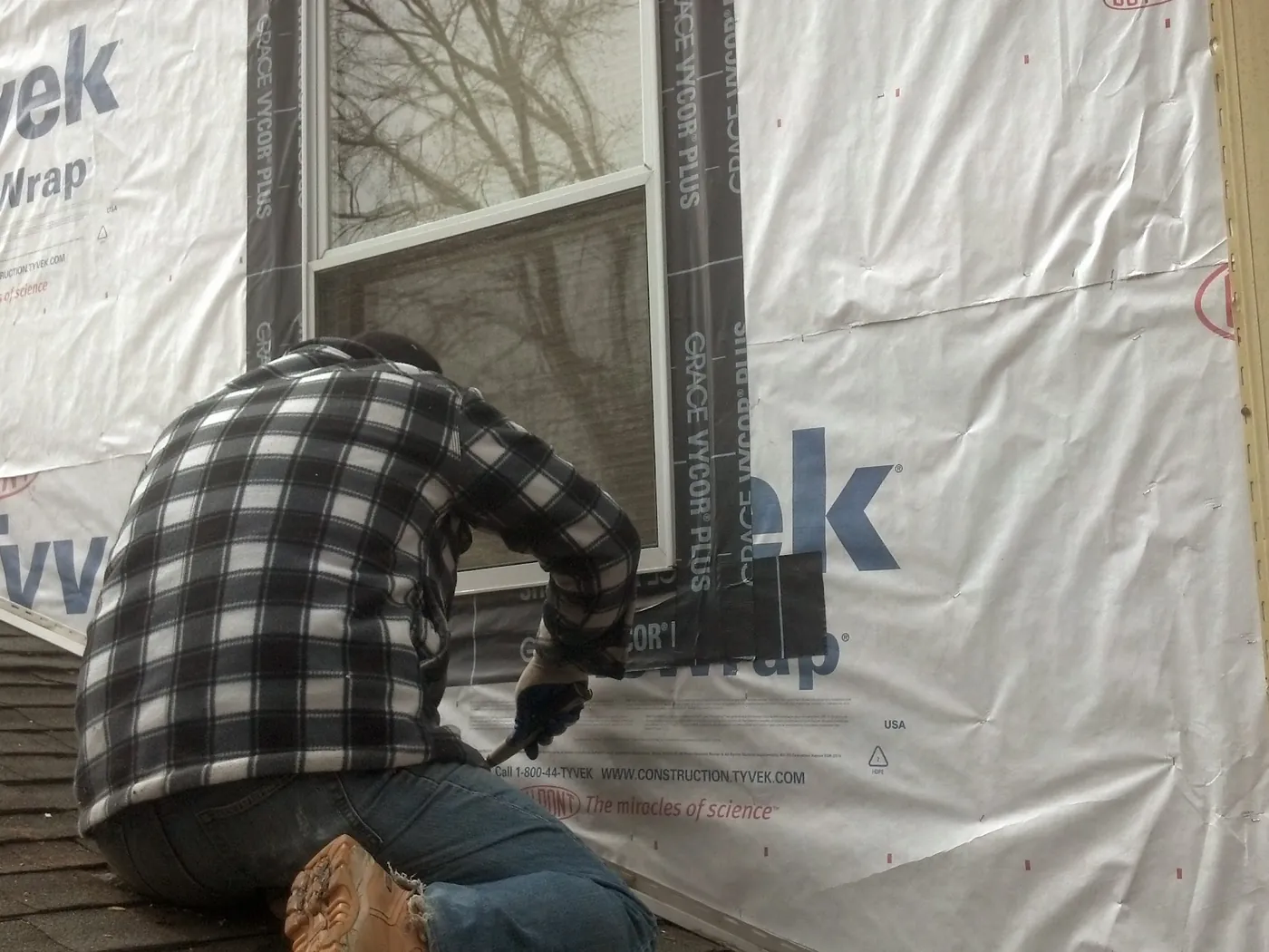 Self-adhered flashing tape being applied over housewrap around a new window opening on a Monmouth County, NJ home